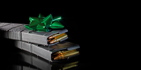 AR-15 magazines loaded with cartridges with a green Christmas bow on a black background and space...