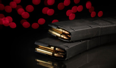 AR-15 magazines loaded with ammo with red Christmas lights behindの写真素材