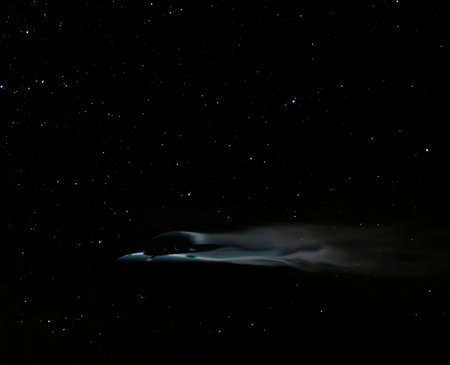 Fast flying saucer moving across a night sky with starsの写真素材