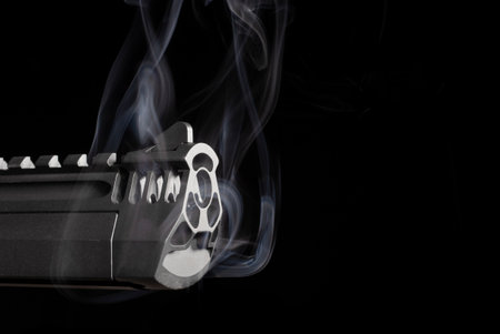 Copy space next to a semi-automatic pistol with smoke on blackの写真素材