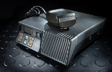 Emergency 911 notice on the screen of a first-responder transceiver with a microphone on top.