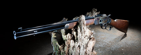 Cowboy style lever action rifle with colorful oiled stock and color casehardened receiver resting...