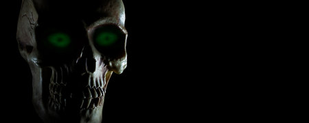 Skull with glowing green eyes and copy space on blackの写真素材