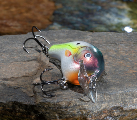 Bright fishsing bait on a rock with water behindの写真素材