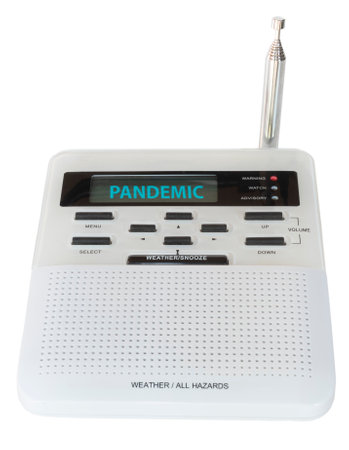 Wireless weather and all hazards radio that has sounded an alarm and is displaying a pandemic warning on its screen.の写真素材