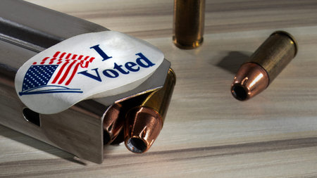Metal pistol magazine with an I voted sticker and cartridges nearby.