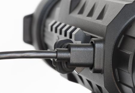 Closeup of the plug on a thermal riflescope used for shooting in the dark as it recharges or downloads photos or videos isolated on a crisp white background.の写真素材