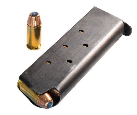 Metal magazine for a semi-automatic 1911 pistol that is fully loaded with cartridges and one round is standing to the side isolated on a white background.の写真素材