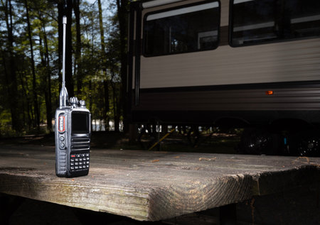 Camping trailer parked at a forested campsite with a two way radio on the picnic table when the sunlight is low.の写真素材