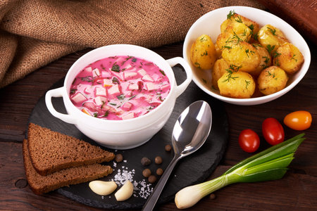 Beetroot soup with sour cream and fried potatoes on the rustic background.