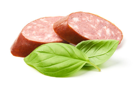 Smoked sausage slices with basil herb, isolated on white backgroundの写真素材