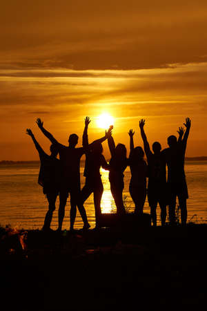 Group of happy friends hands up against the sunsetの写真素材