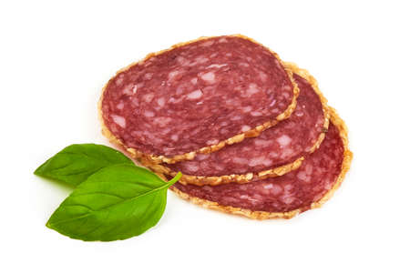 Smoked salami sausages slices with basil leaves, isolated on white background.の写真素材