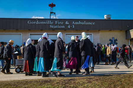 Gordonville, PA, USA - March 10, 2018: Amish women standing outside the fire station at the annual Lancaster County Mud Sale at the Gordonville Fire Company.のeditorial素材