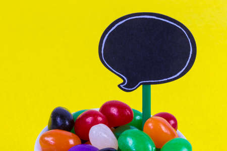 Jelly Beans in cup with blank speech bubble card yellow background horizontalの写真素材