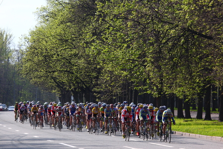 Participants and athletes riding bikes, mass start under green treesのeditorial素材