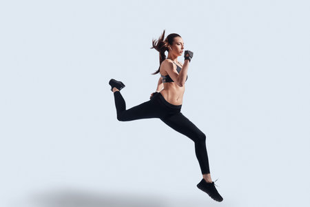 Feeling the freedom. Full length of attractive young woman in sports clothing exercising while...