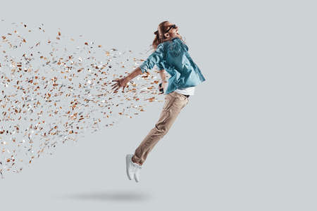 Freedom! Full length of handsome young man keeping arms outstretched while hovering against grey backgroundの写真素材