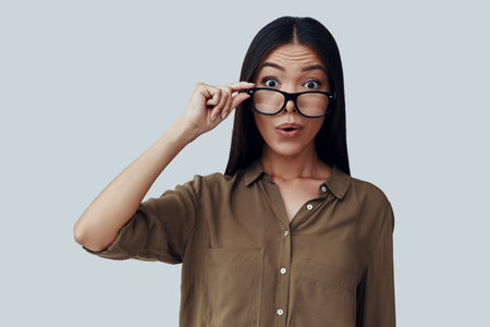 Acting silly. Attractive young Asian woman looking at camera and making a face while standing...