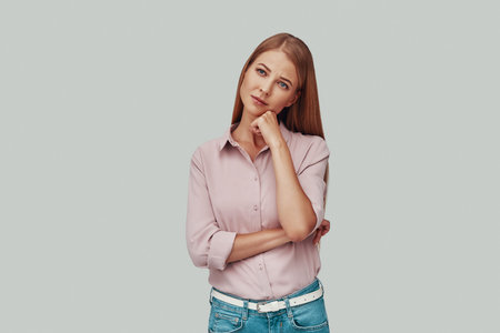 Attractive young woman looking away while standing against grey background