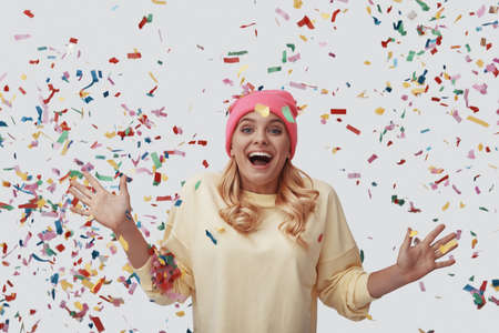 Attractive young woman looking at camera and smiling while standing against grey backgroundの写真素材