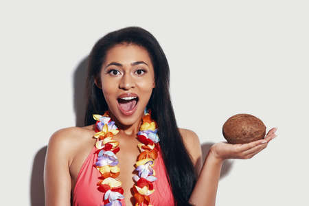 Attractive young woman in bikini looking at camera and keeping mouth open while standing against grey backgroundの写真素材