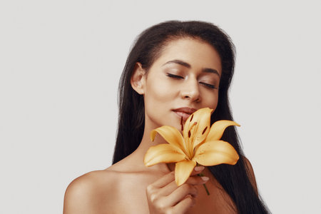 Attractive young woman keeping eyes closed while standing against grey backgroundの写真素材