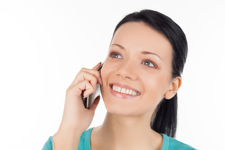 Woman on the phone. Cheerful young woman talking on the mobile phone and smiling while isolated on whiteの写真素材