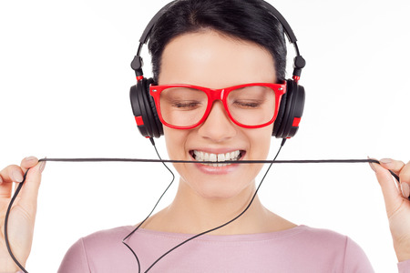 It is her favorite song. Beautiful young woman in red glasses and headphones listening to the music and keeping eyes closed while isolated on whiteの写真素材
