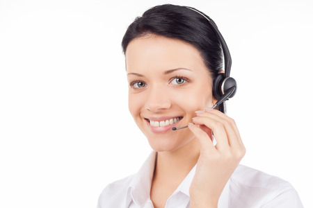 Customer service representative. Beautiful young woman in headset smiling and looking at camera while isolated on whiteの写真素材
