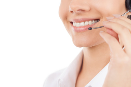 Customer service representative. Cropped image of beautiful young woman in headset smiling while isolated on whiteの写真素材