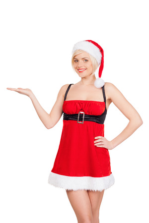 Your advertisement in her hand. Beautiful young woman in Santa costume holding a copy space and smiling while standing isolated on whiteの写真素材