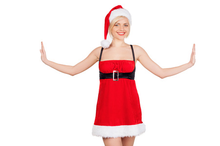Santa girl. Beautiful young woman in Santa costume stretching out her hands and smiling while standing isolated on whiteの写真素材