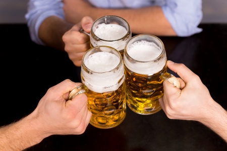 Cheers! Close-up top view of people holding mugs with beerの写真素材