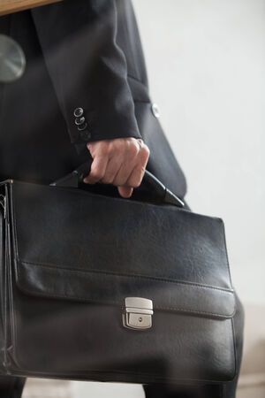 Moving up. Cropped side view image of man in formal wear carrying a briefcase and moving up by stairs の写真素材