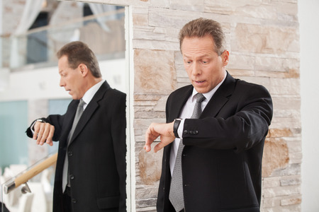 Late again. Worried mature man in formalwear checking a time の写真素材