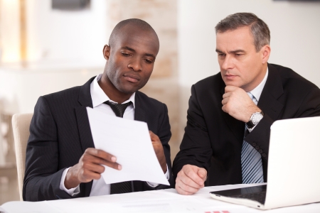 Discussing a project. Two confident business people in formalwear discussing something while one of them pointing a paperの写真素材