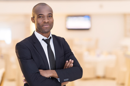 Confidence and charisma. Cheerful young African man in full suit keeping arms crossed and looking at cameraの写真素材