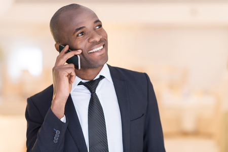Businessman on the phone. Cheerful young African man in formalwear talking  on the mobile phone and smilingの写真素材