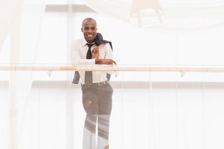 Confident businessman. Low Angle view of cheerful young African man in shirt and tie looking at camera and smilingの写真素材