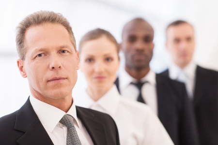 Business team. Confident mature man in formalwear looking at camera while his colleagues standing in line behind himの写真素材