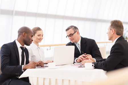 Business meeting. Business people in formalwear discussing something while sitting together at the tableの写真素材