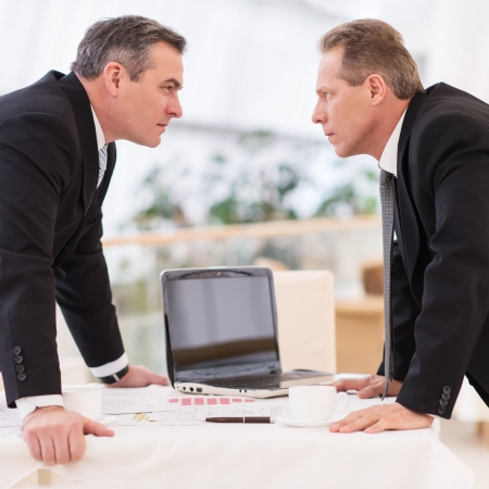 Business confrontation. Two mature men in formalwear conflicting while standing face to faceの写真素材