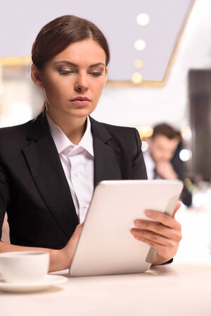 Businesswoman with digital tablet. Beautiful young woman in formalwear working on digital tablet while sitting at the restaurantの写真素材