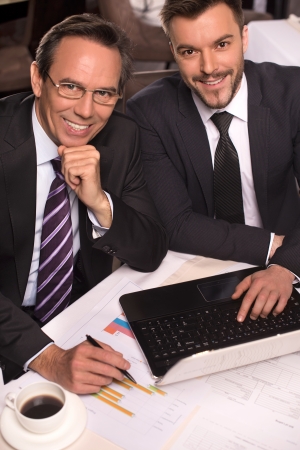 Business people. Top view of two business people in formalwear smiling at camera while working on laptopの写真素材
