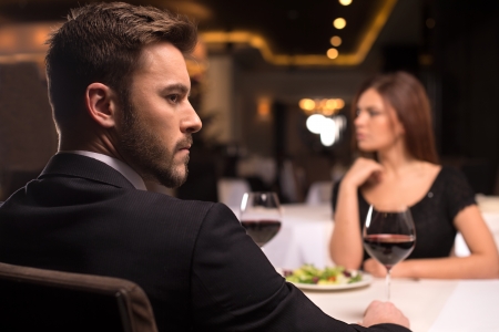 No more words. Thoughtful young couple sitting at the restaurant and looking awayの写真素材