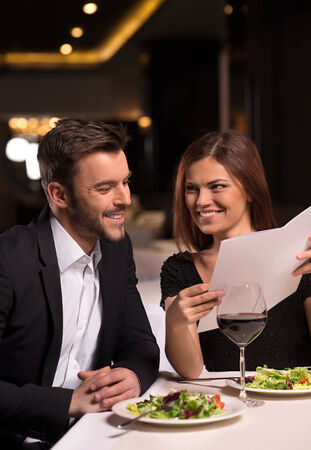 She knows what she wants. Beautiful young looking at the menu and smiling while sitting at the restaurantの写真素材