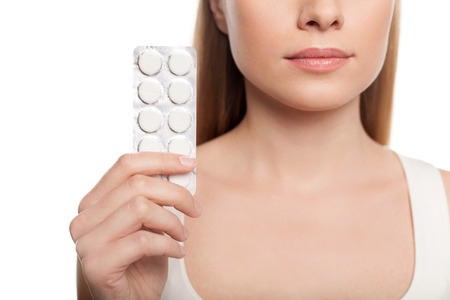 Take your pills. Cropped image of young woman holding pack of pills while isolated on white の写真素材