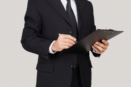 Making notes. Cropped image of man in formalwear keeping arms crossed and smiling while standing against grey background の写真素材