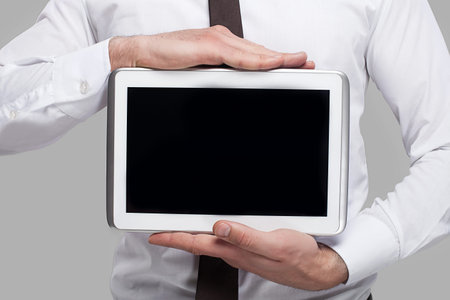 Join a digital age. Cropped image of man in formalwear holding a digital tablet while standing...